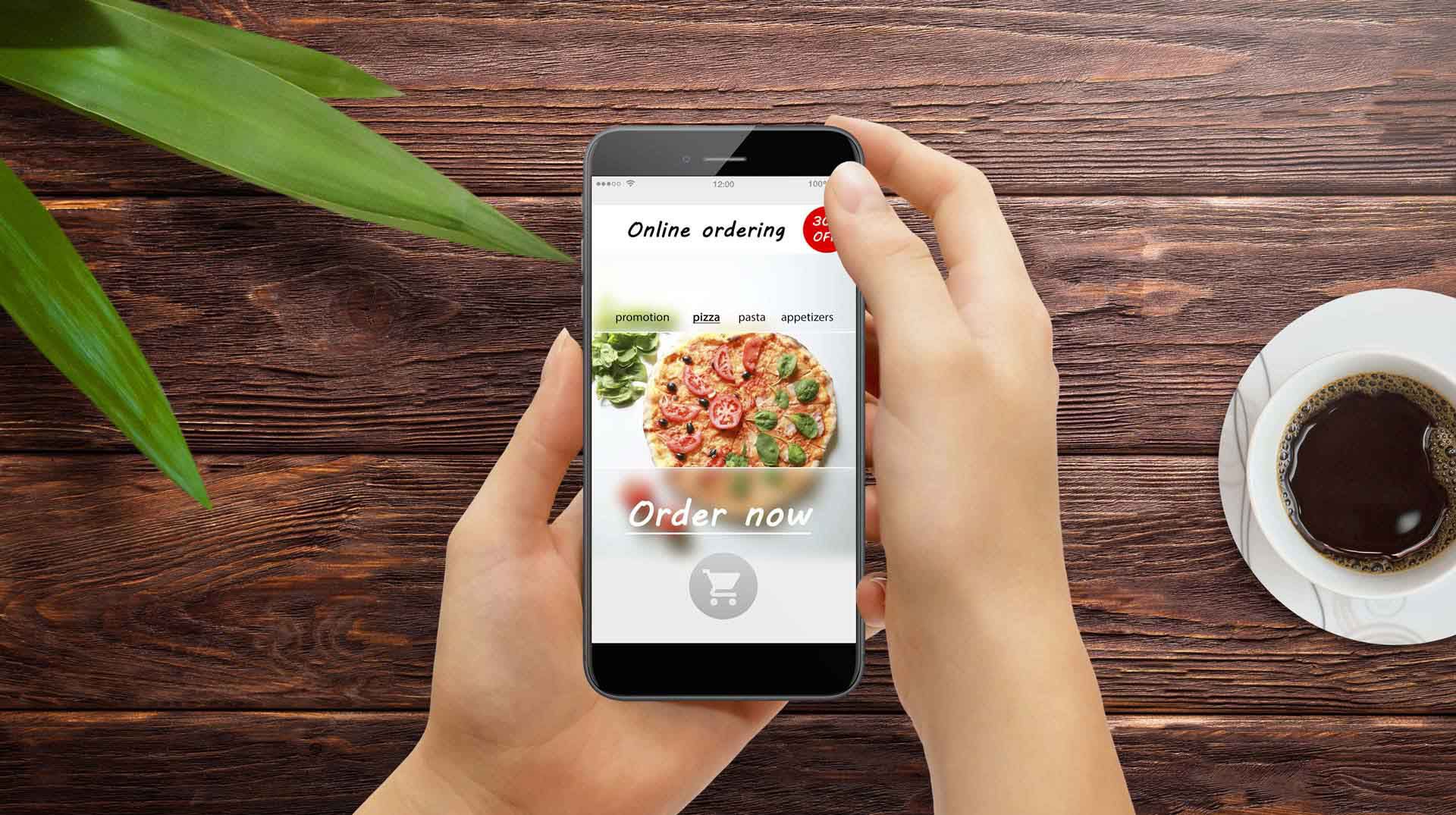 Two hands holding a mobile phone that is displaying a pizza ordering application onscreen